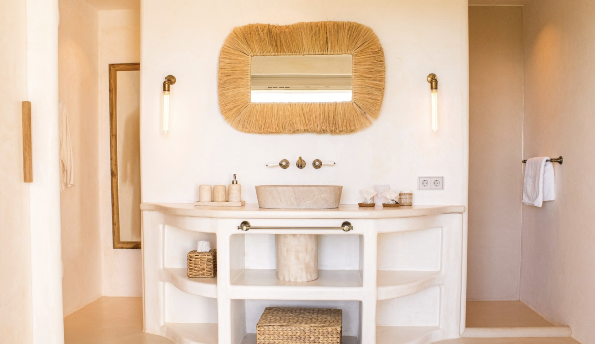Bathroom vanity with a rustic mirror, wall-mounted lights, and accessories including soap dispensers, tissue box, and towels.