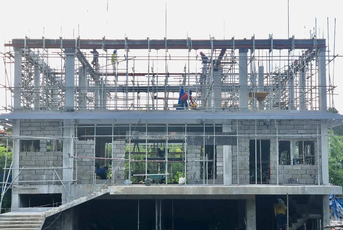Construction workers building a multi-story structure with scaffolding and concrete blocks.