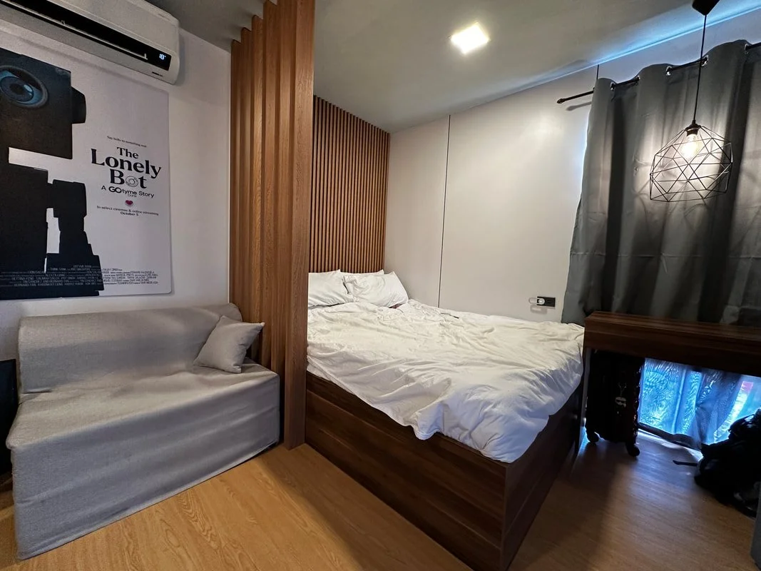 A bedroom with a bed, a sofa, a wall poster, and a window with curtains.