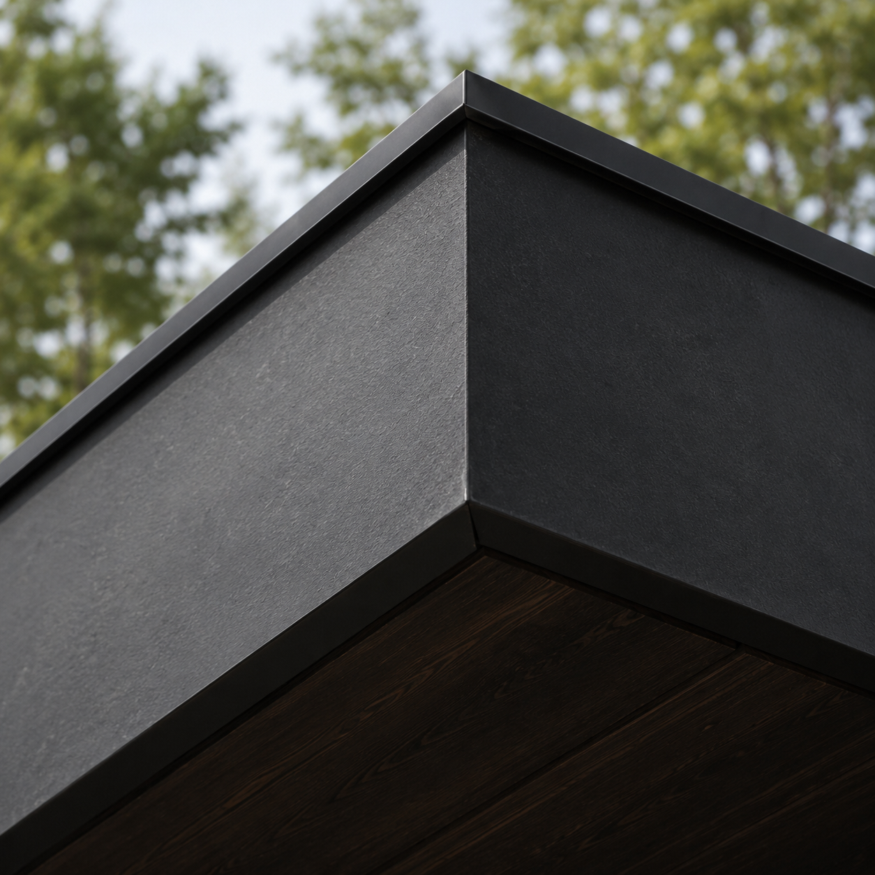 Close-up of a building corner with black textured siding and wooden panels, with blurry green trees in the background.