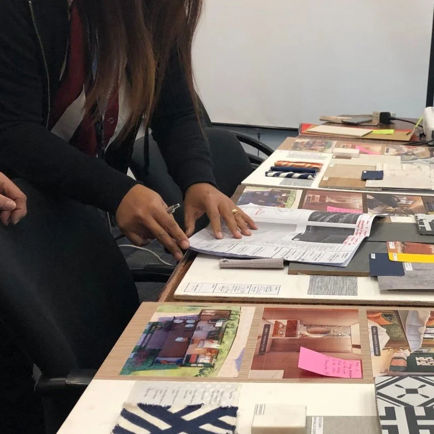 Person looking over a table filled with interior design materials, magazines, color swatches, paint samples, and design plans.