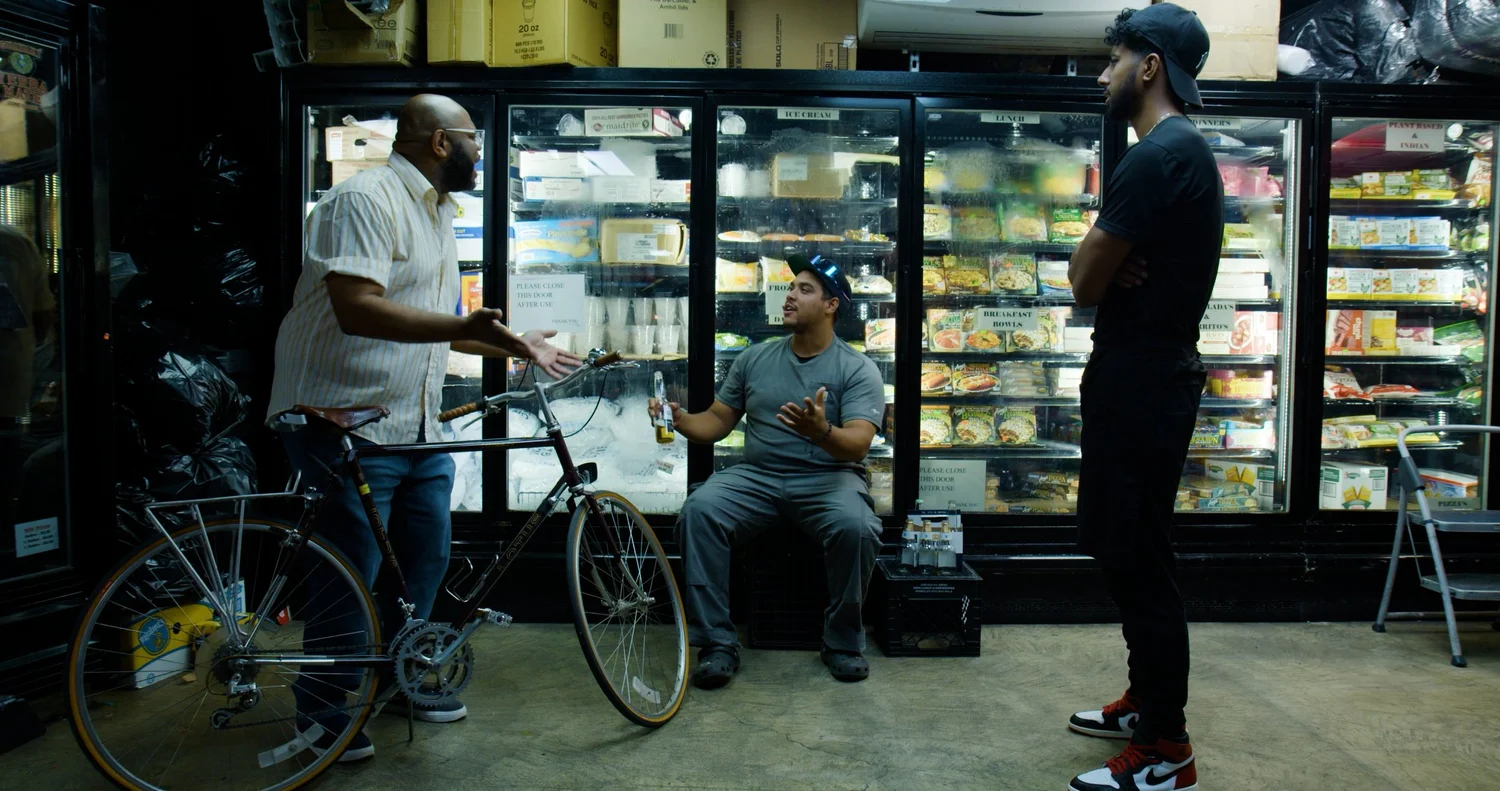 Three men talk beside the store's freezer cases.