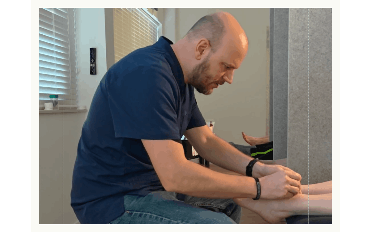 A man receiving a foot massage in a room with windows and blinds.