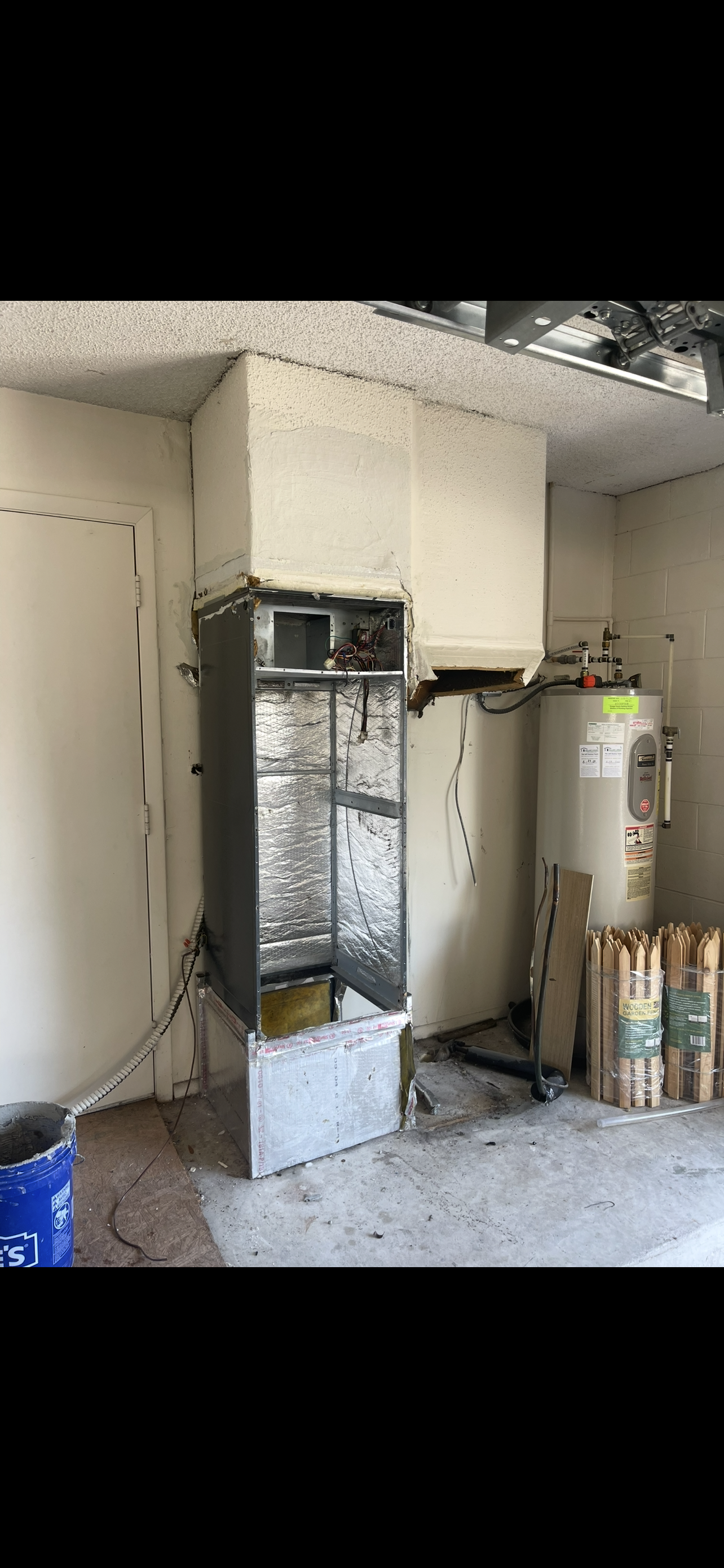 Room with an HVAC or electrical cabinet being installed, water heater, and construction materials.