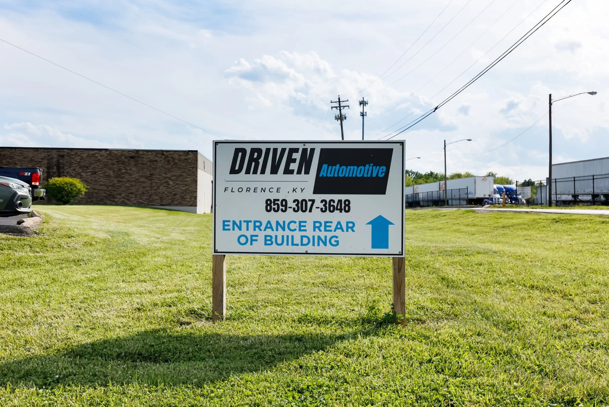 Sign indicating Driven Automotive location with city and phone number, and directing to entrance at rear of building.