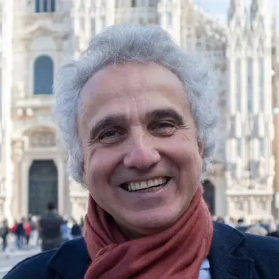 Ritratto di una donna con capelli castani, indossa un berretto nero e un vestito nero, sfondo color marrone.