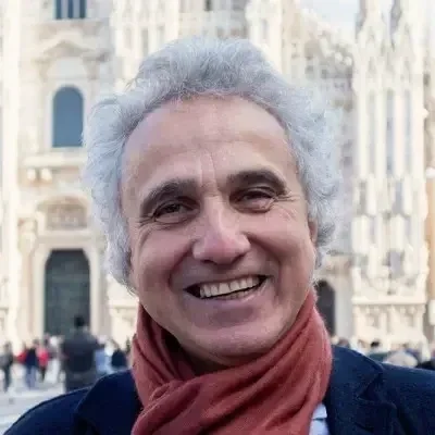 Ritratto di una donna con capelli castani, indossa un berretto nero e abbigliamento nero, sfondo marrone.