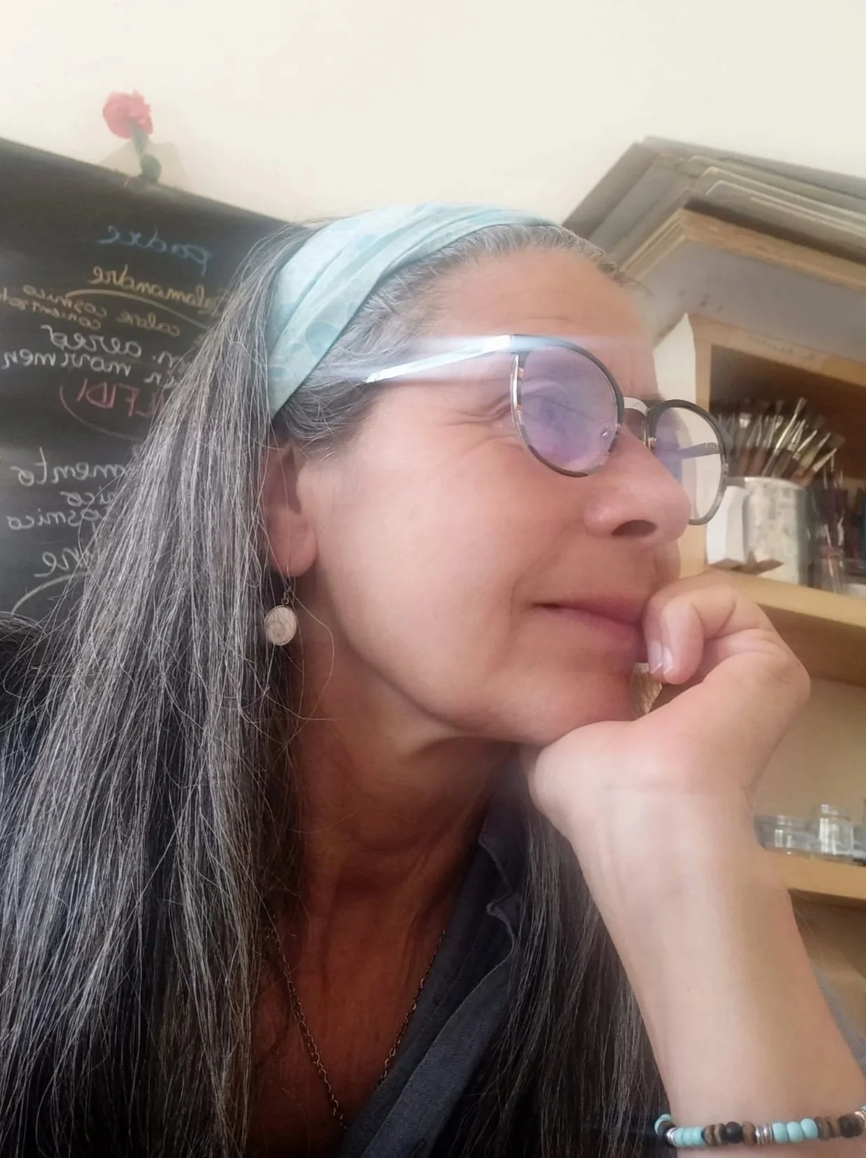 Dipinto di una donna con capelli castani lunghi, abbigliamento storico, in piedi contro sfondo nero.