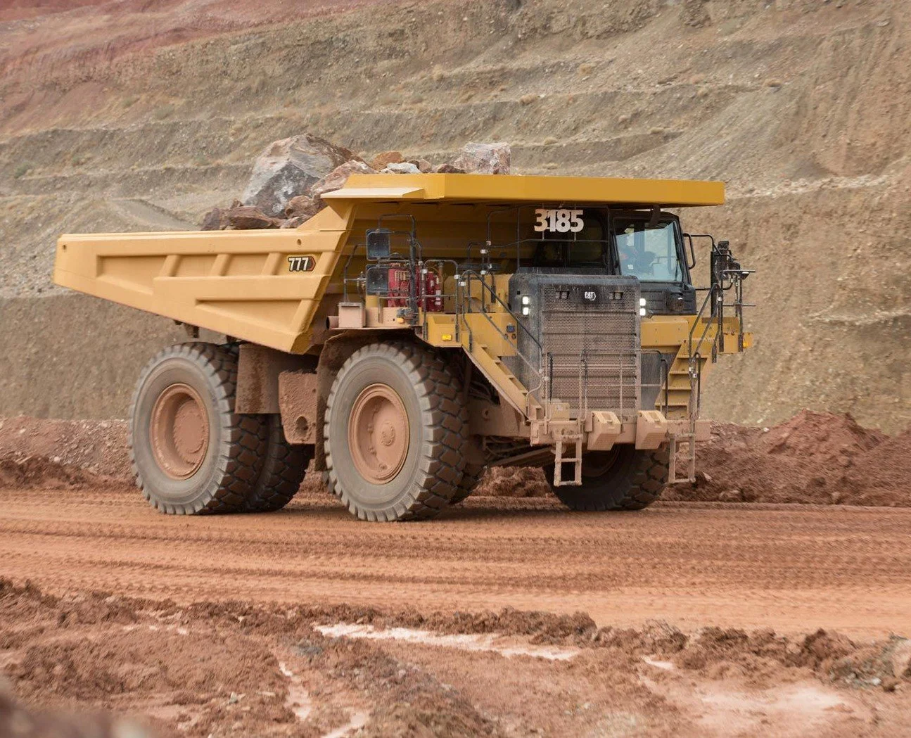 A large yellow articulated dump truck hauling dirt and rocks at a construction or mining site.