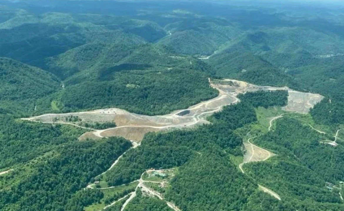 Aerial view of a mountain landscape with winding roads and forested hills.