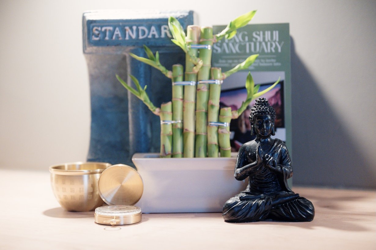 Buddha statue surrounded by bamboo and feng shui books in a calm, balanced home setting