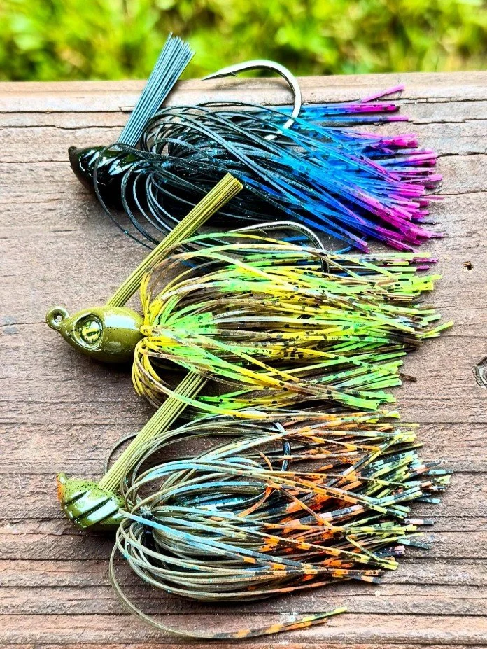 Picture of three multicolored fishing jigs laid out on a wood plank