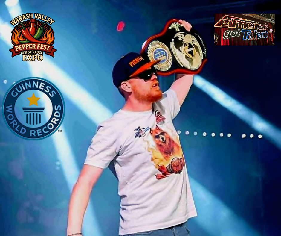 A man with red hair and a beard wearing a black cap, black sunglasses, and a white t-shirt featuring a lion graphic. He is holding a championship belt above his head. The background includes spotlights, with logos for Wabash Valley Pepper Fest, Guinn