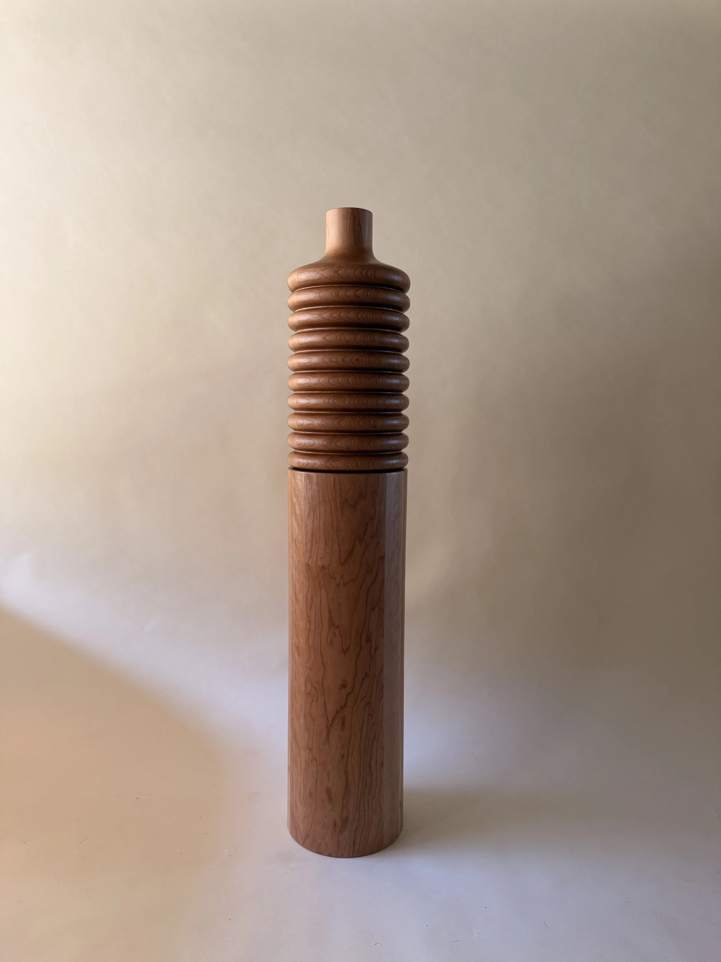 A wooden object with a tall cylindrical base and a ribbed, rounded top.
