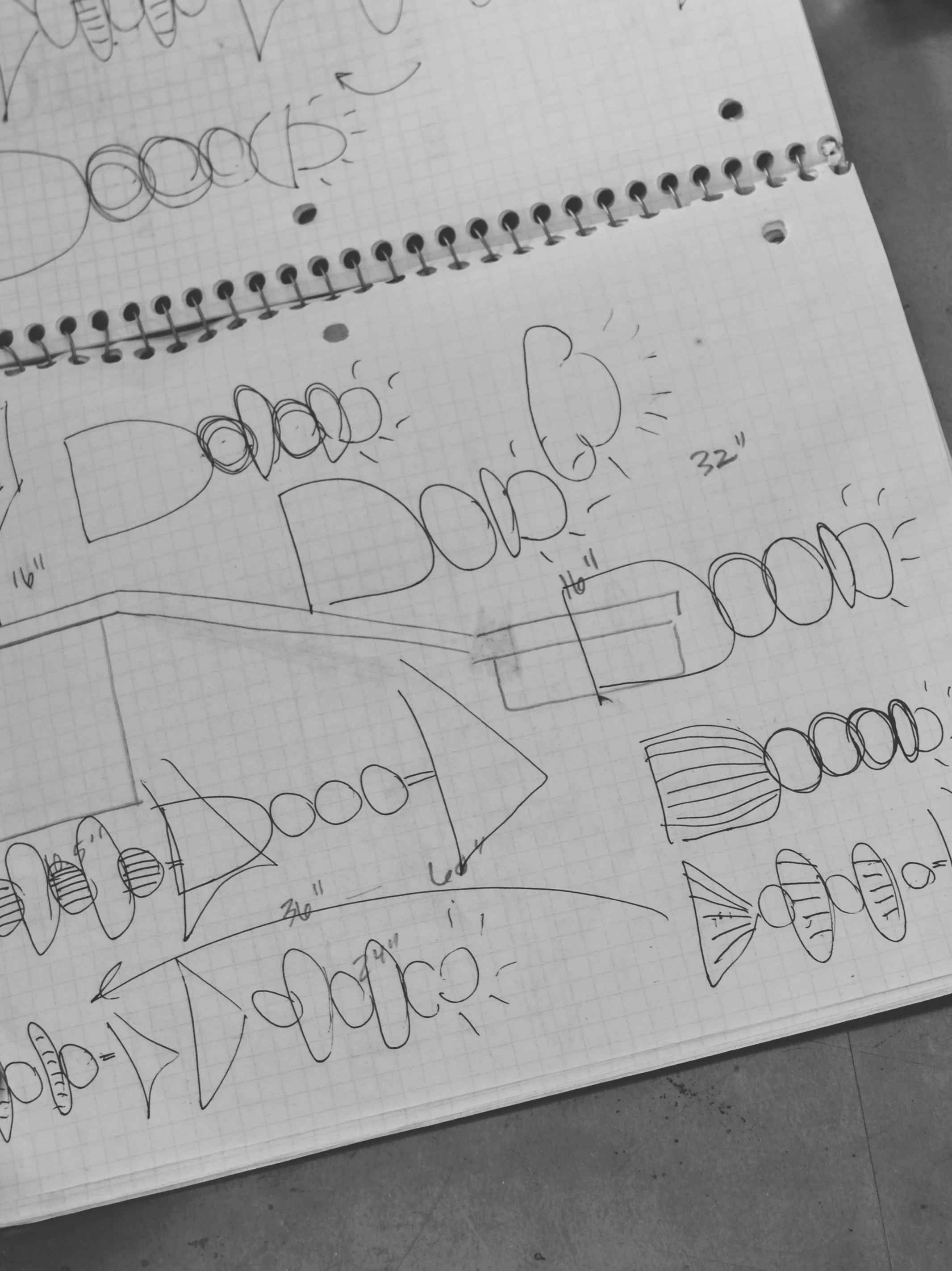 Sheet of graph paper with various hand-drawn sketches and diagrams of different shaped objects, including circles, rectangles, and lines, with some measurements and notes.