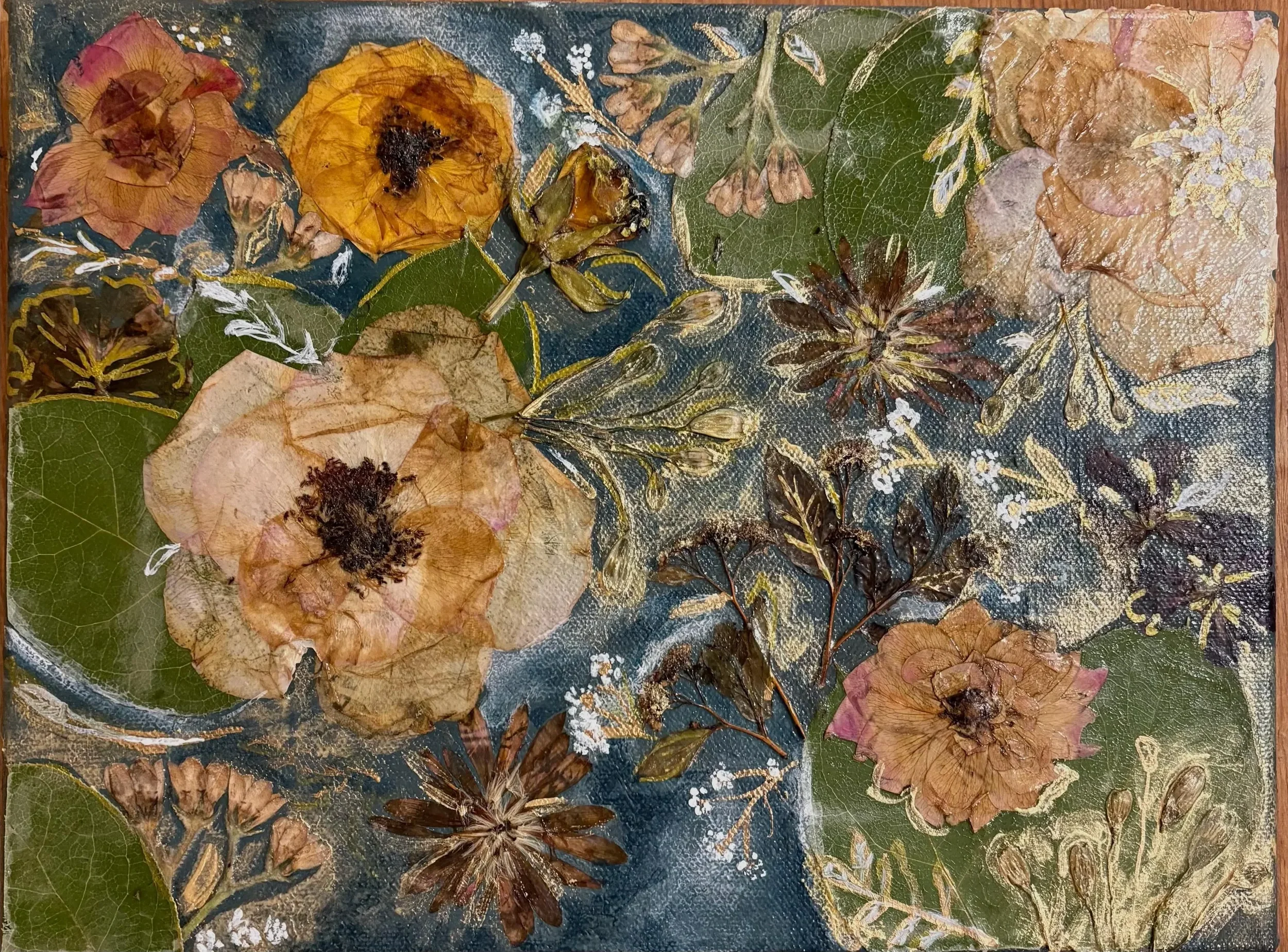 A collage of pressed flowers and leaves with a dark background and some gold accents.