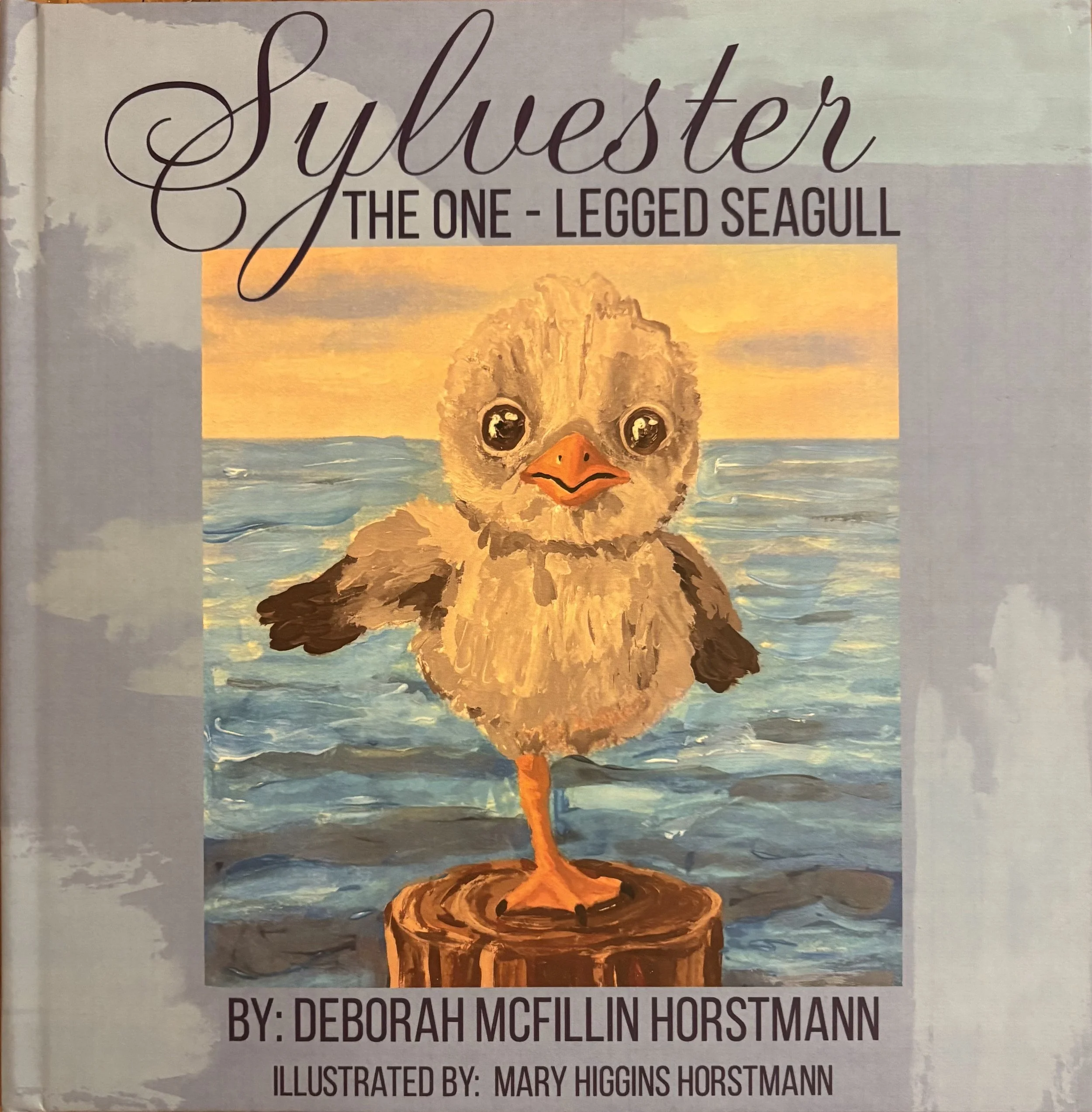 Cover of a book titled "Syllabus: The One-Legged Seagull" by Deborah McFillin Horstmann, illustrated by Mary Higgins Horstmann. The cover features an illustration of a seagull standing on a small patch of land with water in the background, during sunset or sunrise.