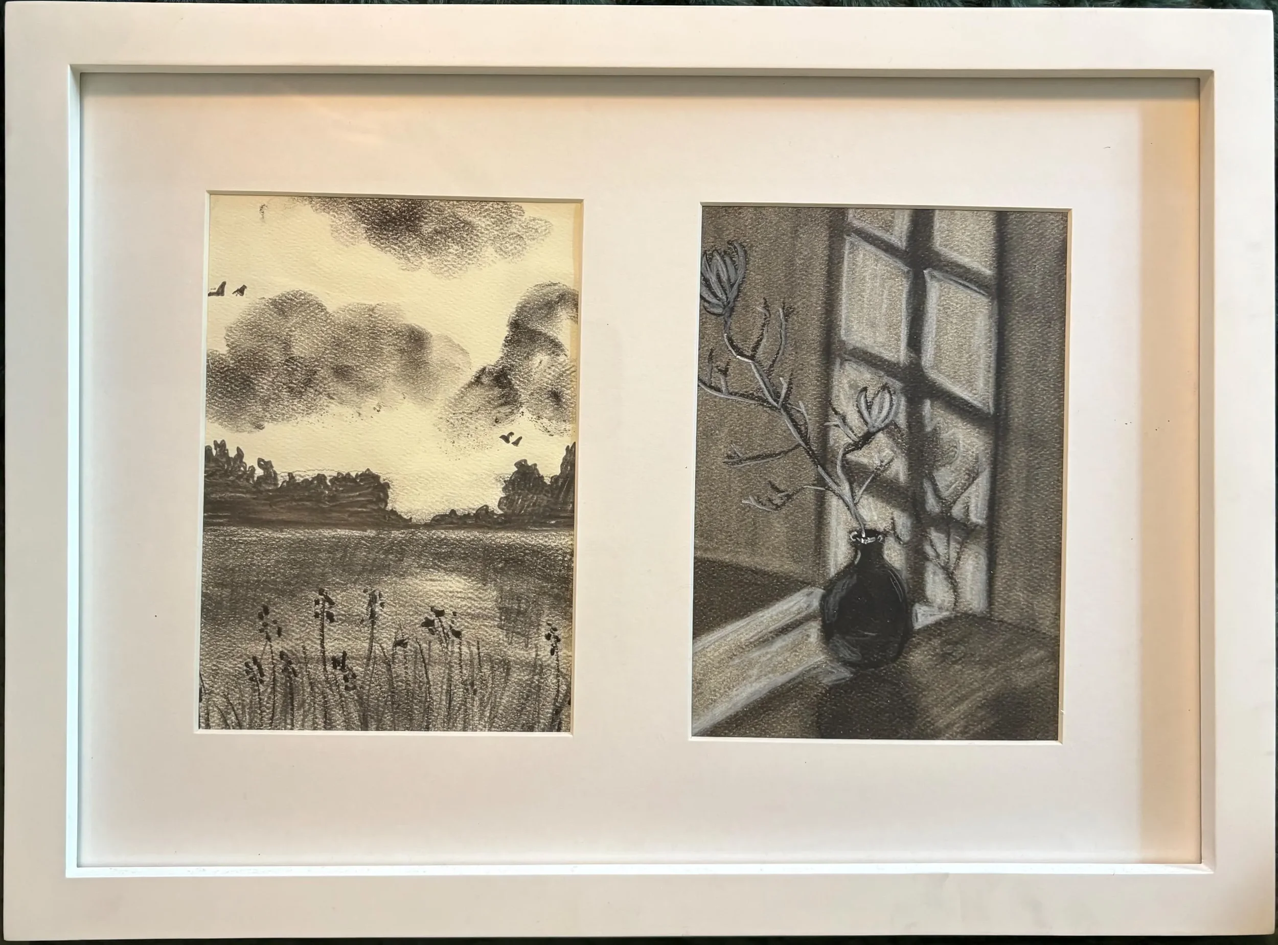 Two black and white framed artworks side by side. The left artwork depicts cloudy skies over trees with a few birds flying, and a body of water in the foreground. The right artwork shows a silhouette of a plant with flowers and a window with diagonal panes in the background.