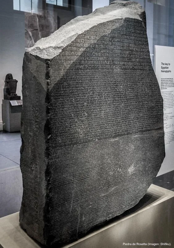 A large black stone slab with engraved ancient Egyptian hieroglyphs displayed in a museum.