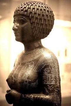 Ancient Egyptian statue of a woman with a detailed hairstyle and engraved symbols on her body