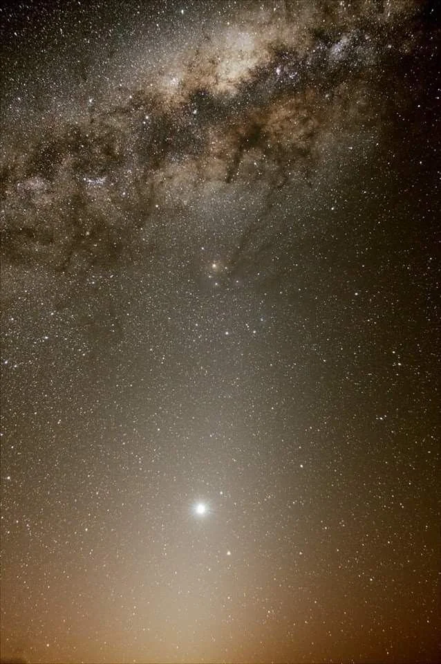 Night sky photo showing the Milky Way galaxy with numerous stars and a bright planet near the horizon.