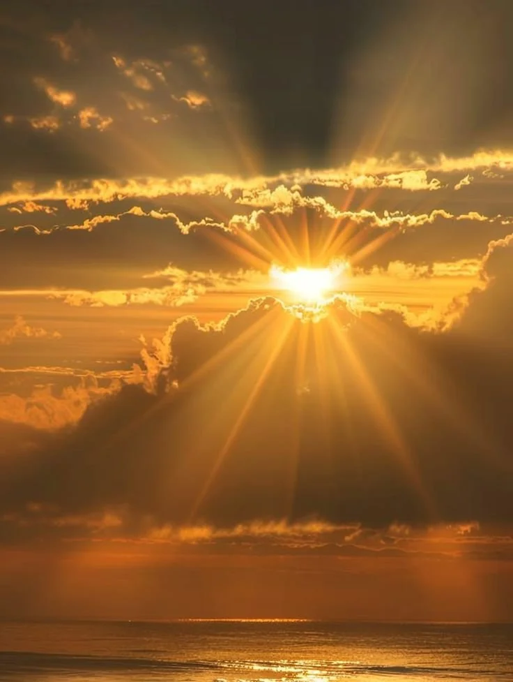 Sunset over the ocean with golden clouds and sun rays.