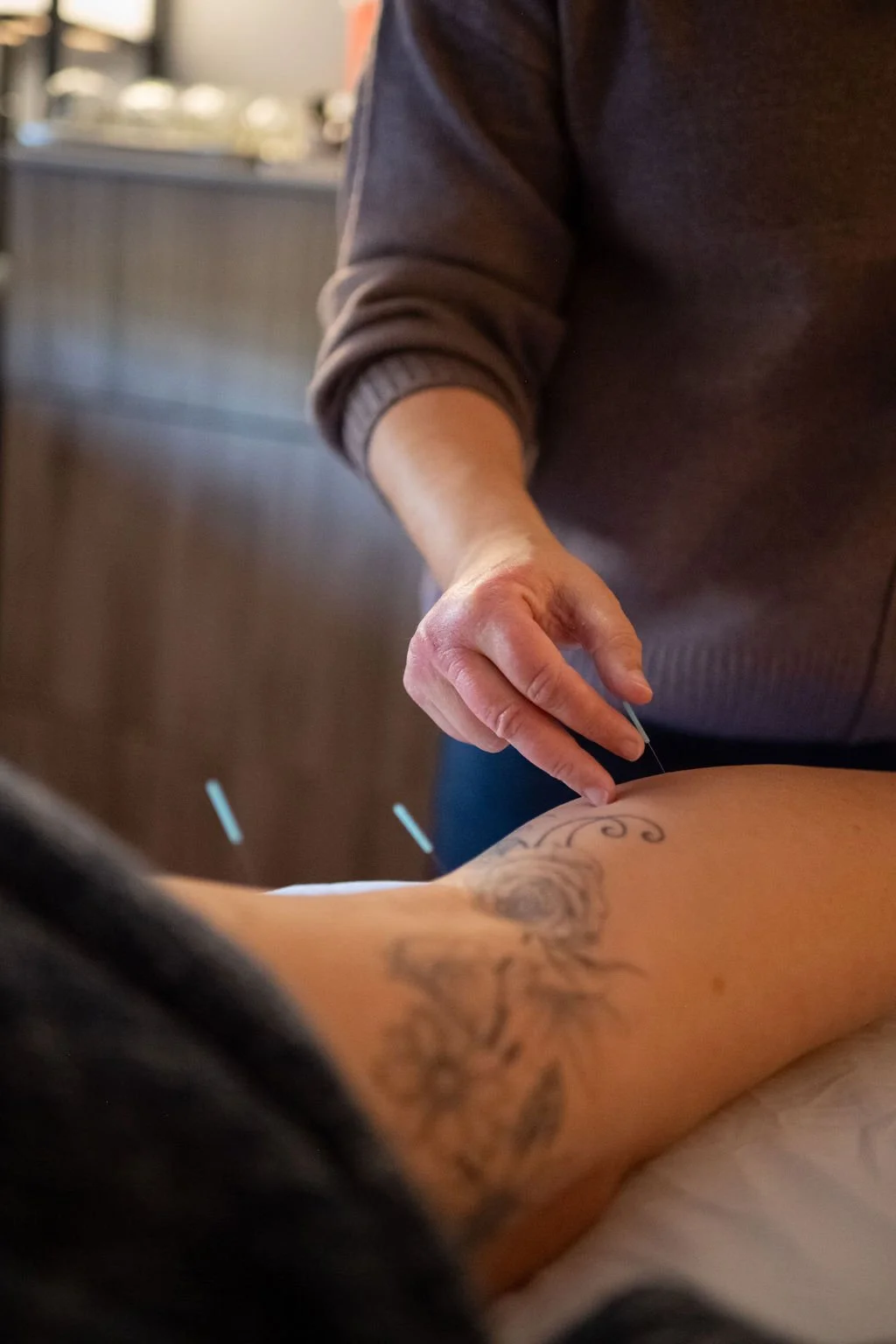 A person receiving a tattoo on their forearm from a tattoo artist in a studio.