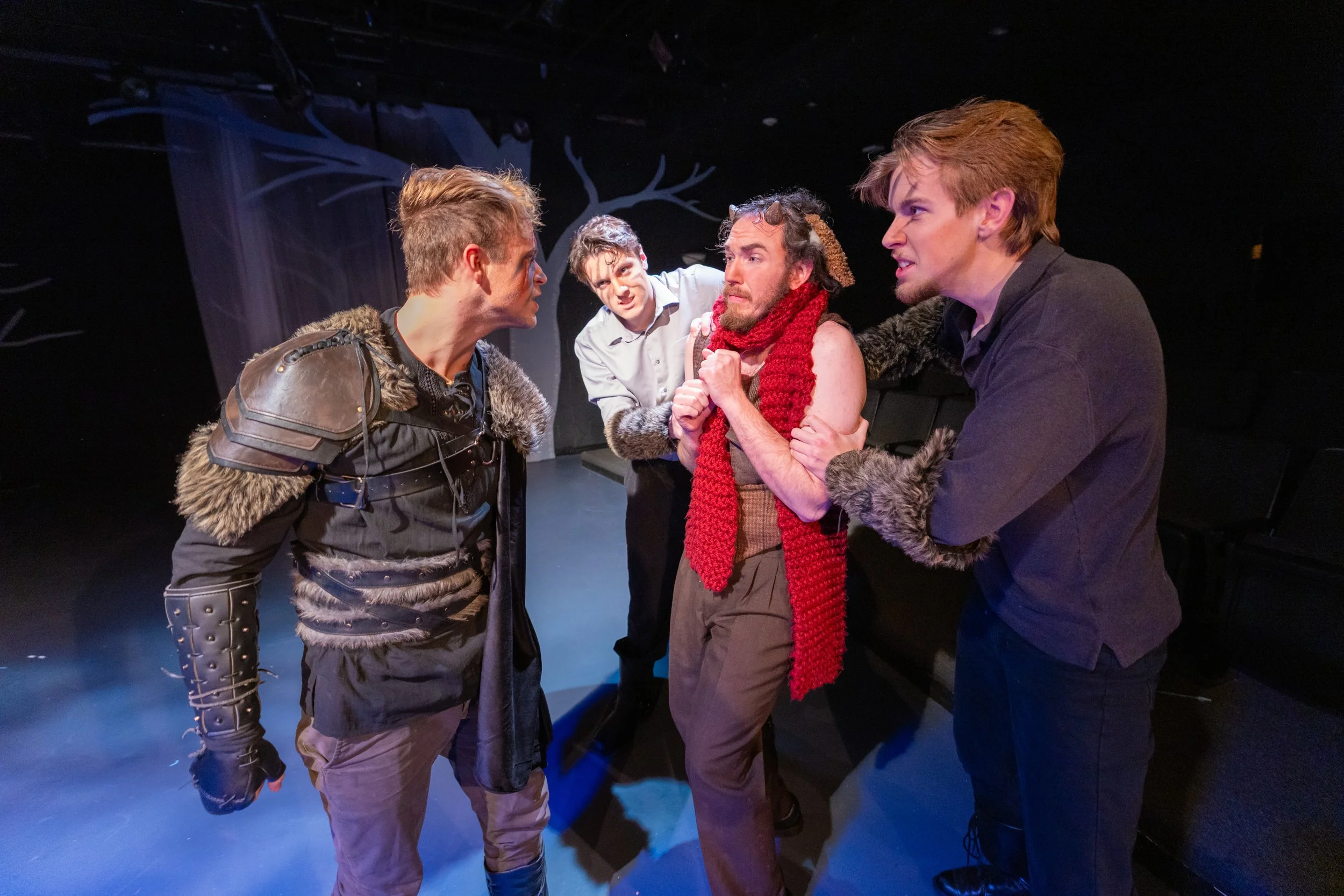 Four actors are on stage, engaged in a dramatic scene. They are in costumes, with intense facial expressions and gestures. Picture of Jed Johnson as Fenris Ulf in the Lion, the Witch, and the Wardrobe 2026 BJU.