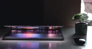 Open laptop with a colorful keyboard and a small potted plant on a desk