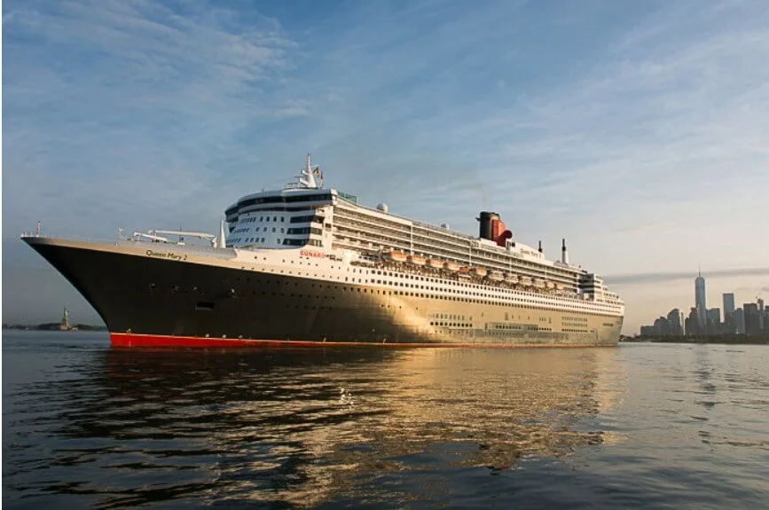 QUEEN MARY 2 with the Statue of Liberty and Lower Manhattan skyline.