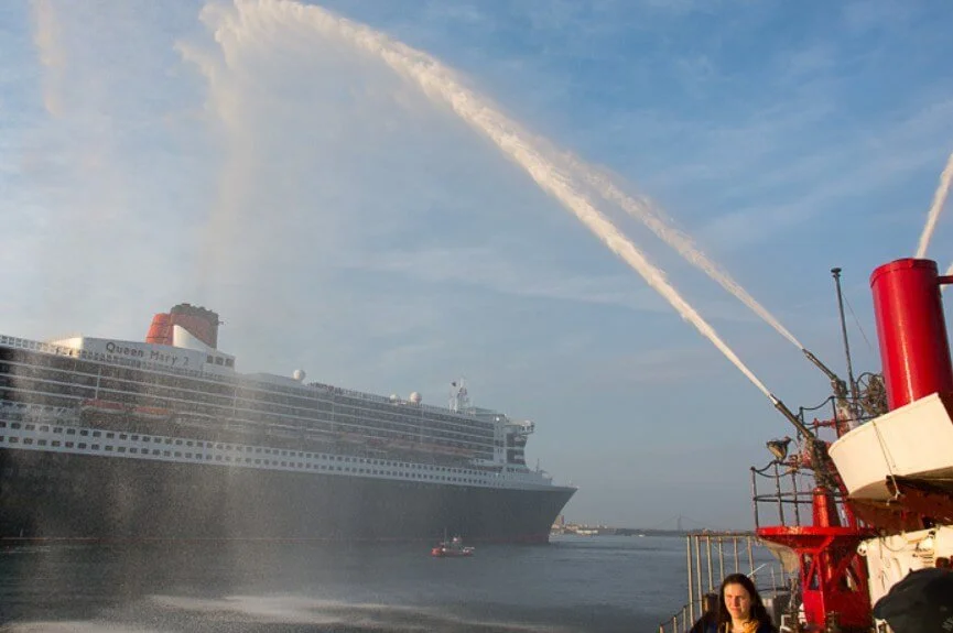 Fireboat JOHN J. HARVEY salutes QUEEN MARY 2 at her Brooklyn berth.