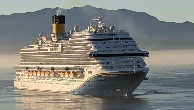Carnival FIRENZE in Ensenada, MX. A large cruise ship sailing in calm water near mountains.