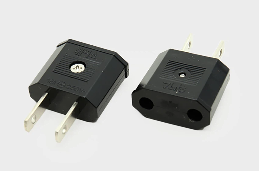 Two black electrical plug adapters, one with prongs visible and the other with socket openings for prongs, placed on a white background.