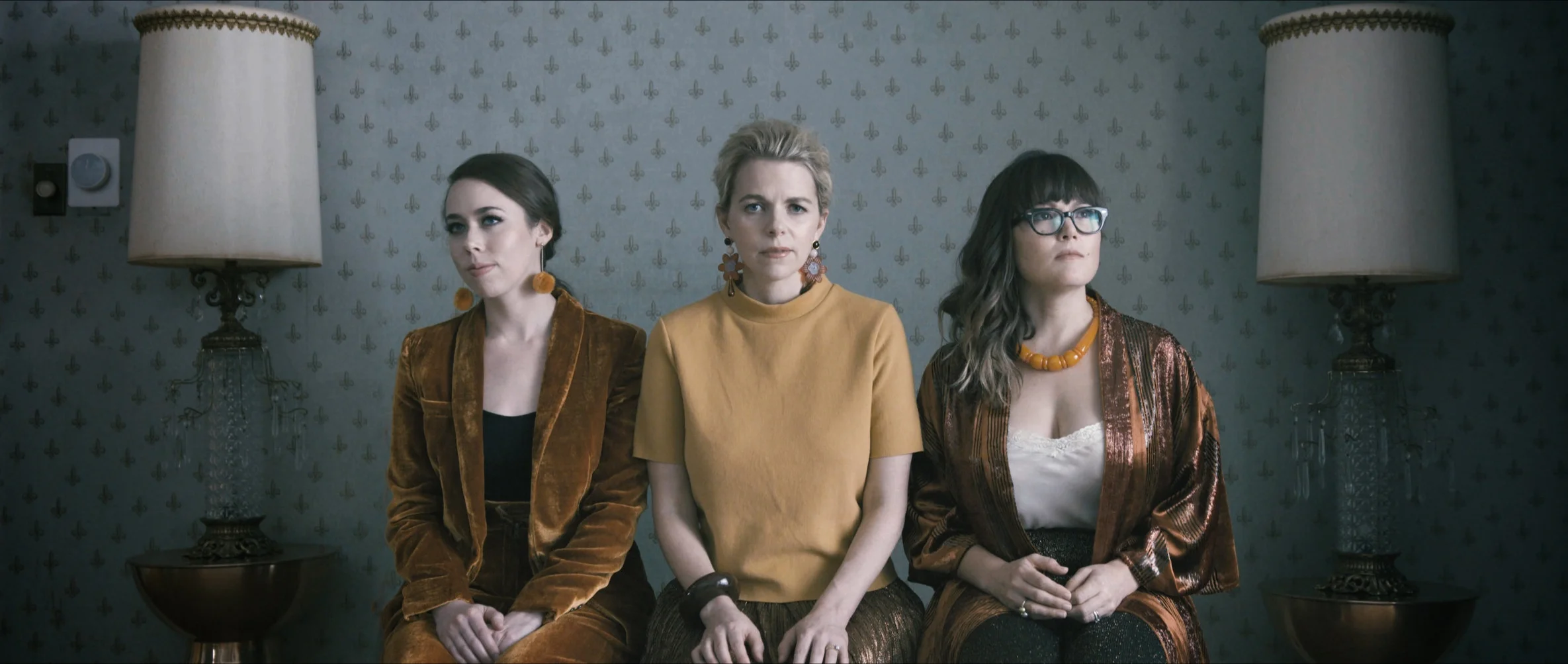 a still image from "Game to Lose" music video with Sara Watkins, Sarah Jarosz, and Aoife O’Donovan sitting together on a bench