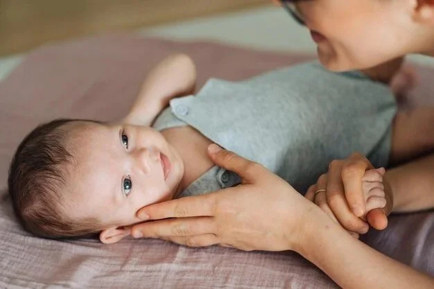 Ein Baby liegt auf einem Bett, betrachtet eine Frau, vermutlich die Mutter, die es liebevoll hält.
