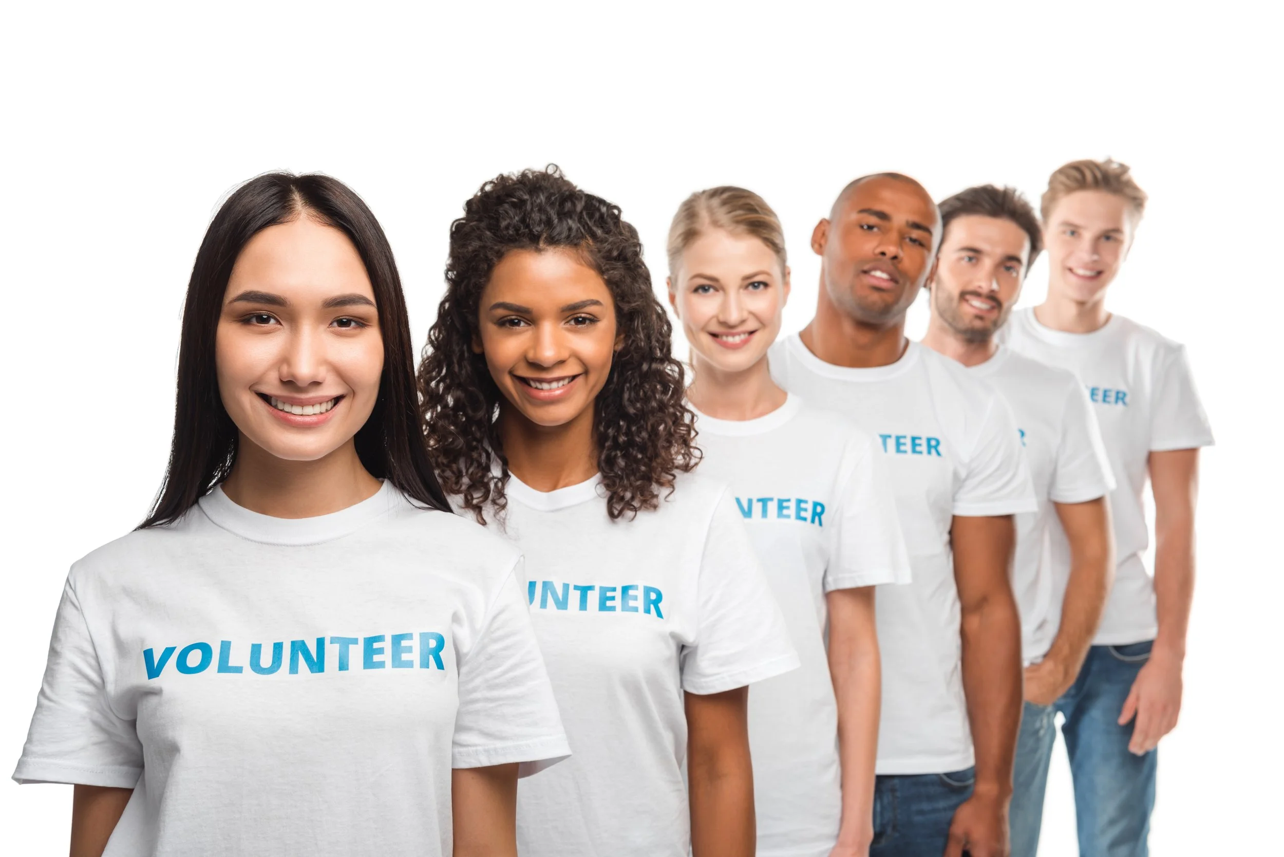 Group of diverse young volunteers standing in a line, smiling, wearing white T-shirts with 'VOLUNTEER' printed in blue.