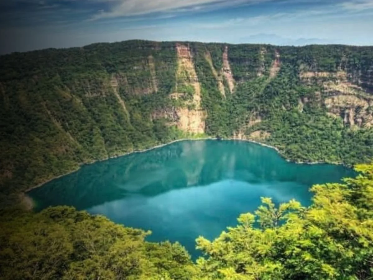 A lake surrounded by steep green forested cliffs.
