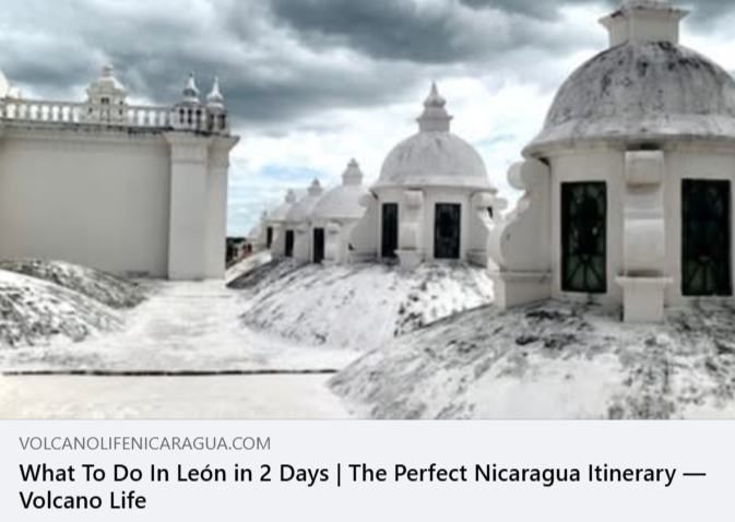 White stone buildings with domed roofs and black windows, the roof of leon cathedral, under a cloudy sky.