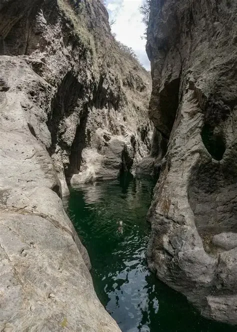 A narrow Somoto canyon with tall rocky walls and a small river flowing through it.