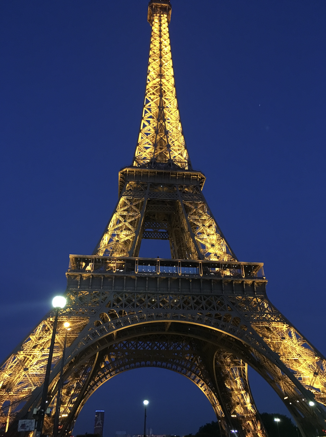 The Eiffel Tower illuminated at night against a dark blue sky.