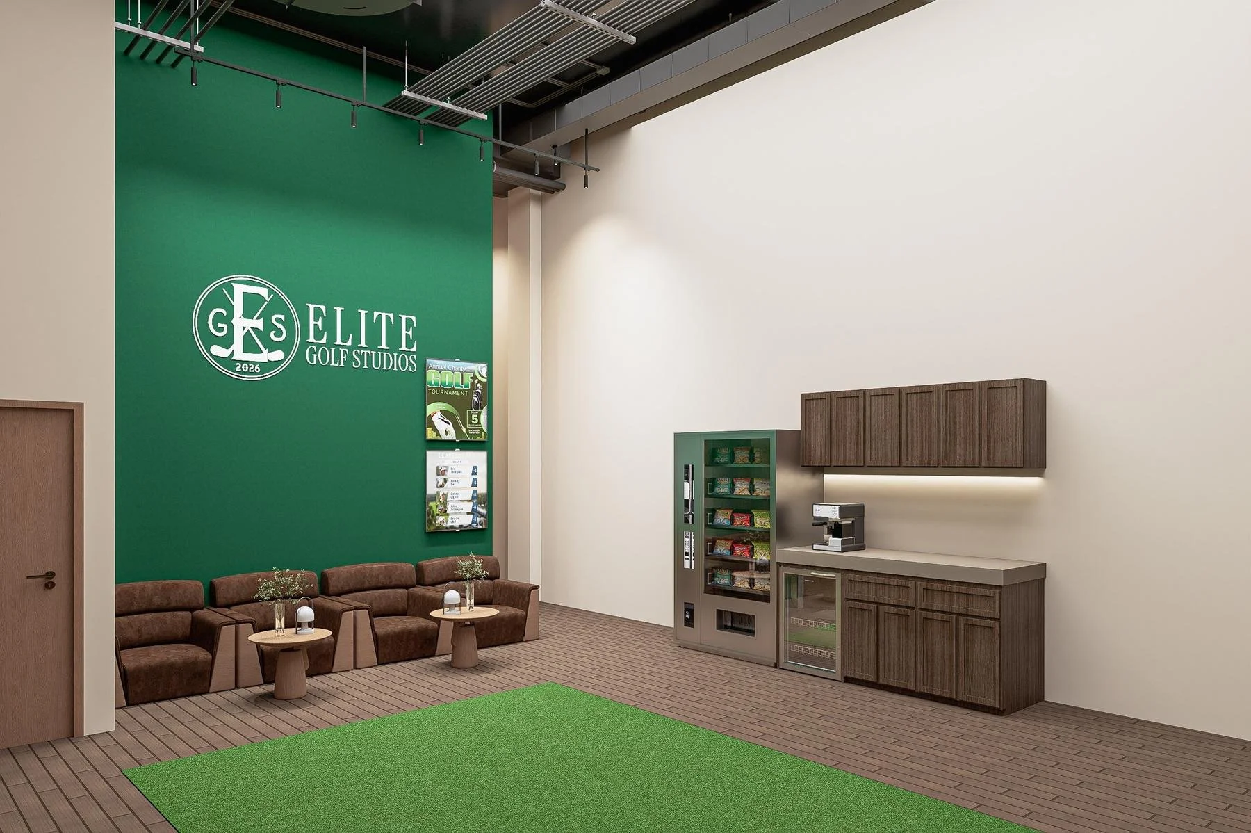 Interior of a golf studio with a green wall displaying the 'Elite Golf Studios' logo. There are brown sofas with small round tables, a vending machine with snacks, a coffee machine, and a wooden cabinet with storage above. The floor has wood flooring and a green mat.