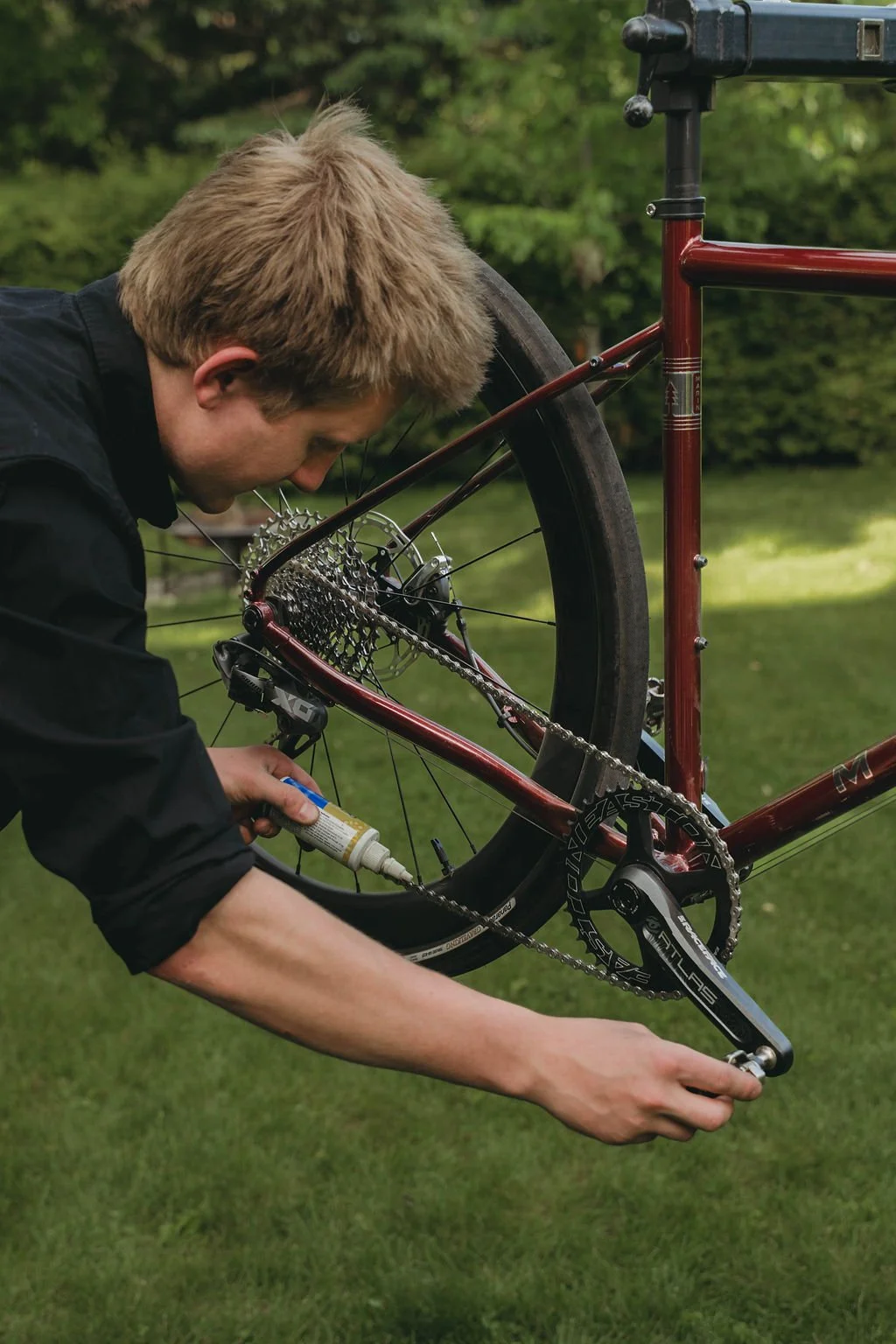 Person repairing a bicycle outdoors, focusing on the chain and gear area.