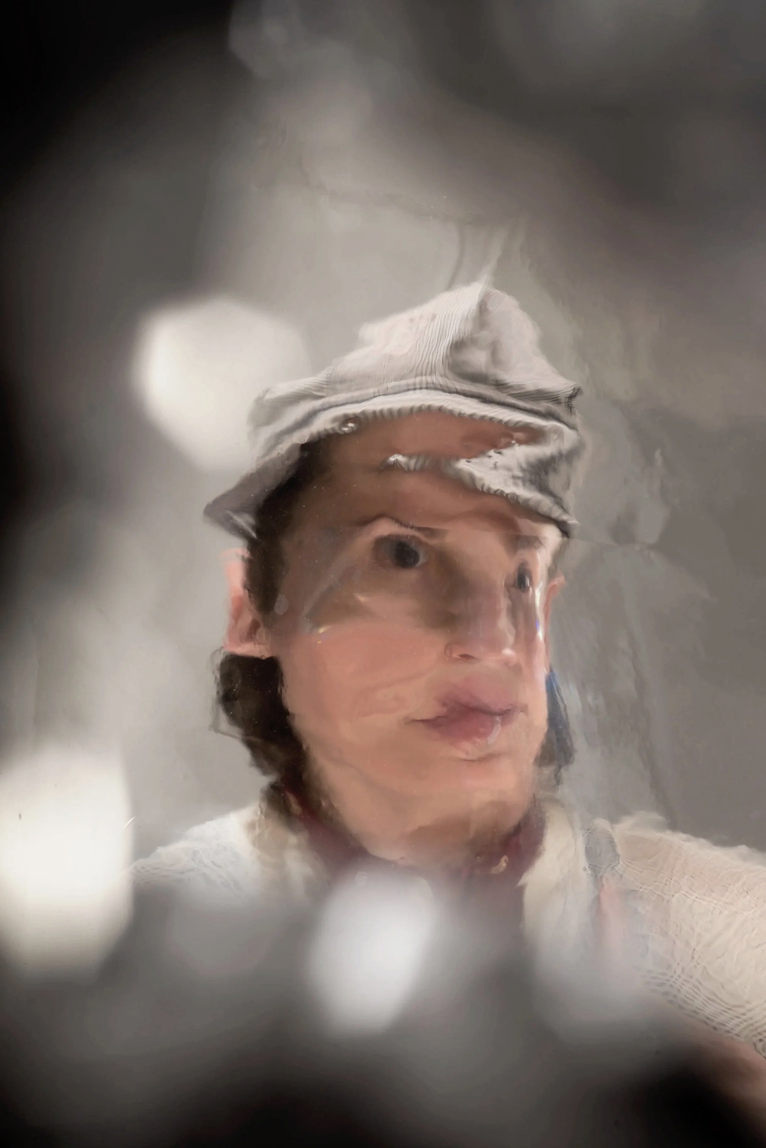 A white nonbinary person with short brown hair wearing a striped hat is caught in a blurry, distorted photo.