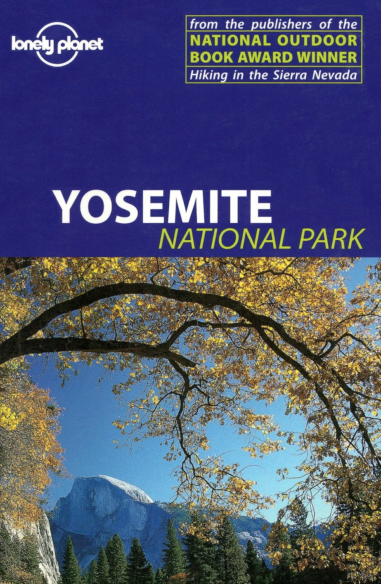 A scenic view of Yosemite National Park on the cover of Lonely Planet's guidebook, featuring mountains, trees with autumn foliage, and a clear blue sky.