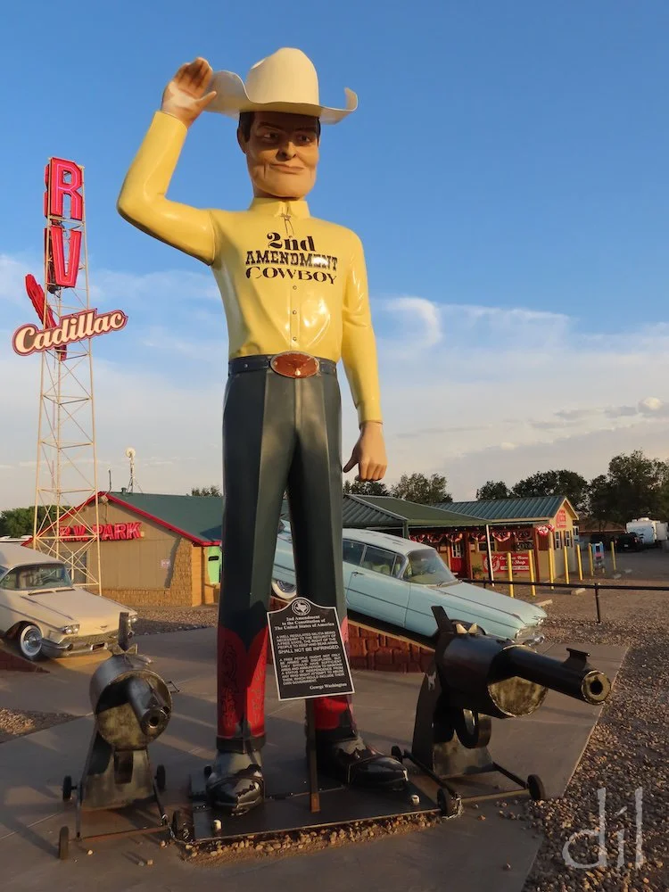 The Second Amendment Cowboy tips his ten-gallon hat toward Cadillac Ranch, just a mile down the road. At his feet are a pair of Colt revolvers and the full text spelling out Americans' right "to keep and bear arms."