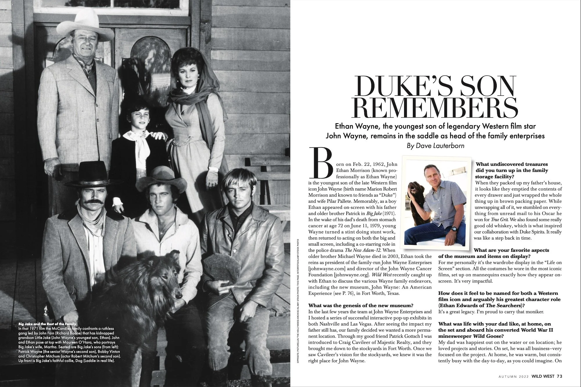 Black and white photograph of a film cast portraying the Wayne family from the movie 'Big Jake,' standing outdoors in front of a wooden barn. The group includes a man dressed as a cowboy in a hat, a woman with a large hairdo, various men in cowboy hats and western attire, a dog, and a child, with a rustic setting behind them.