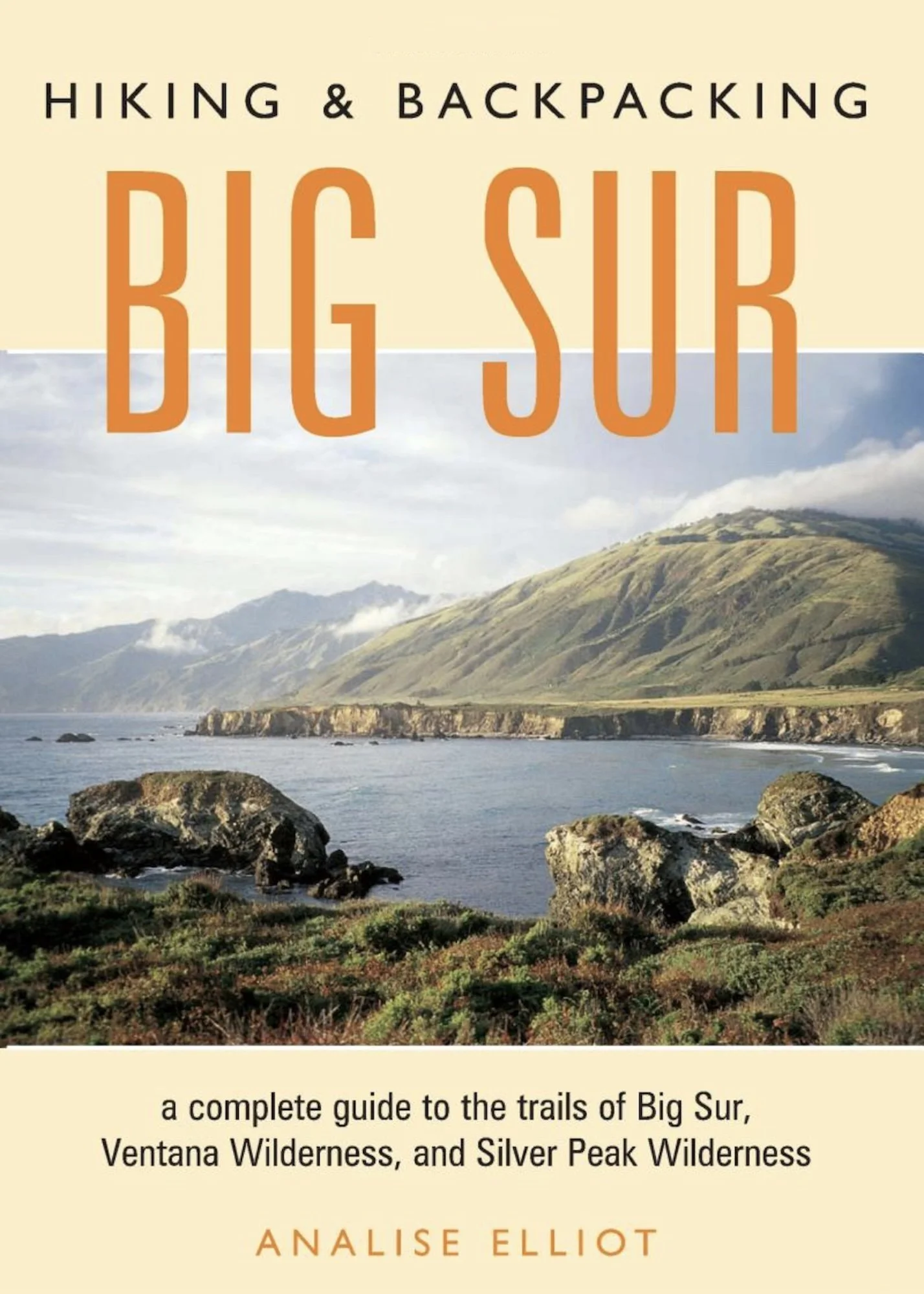 A scenic coastal landscape with mountains, rocky shoreline, and a partly cloudy sky, overlaid with the title of a hiking guidebook.