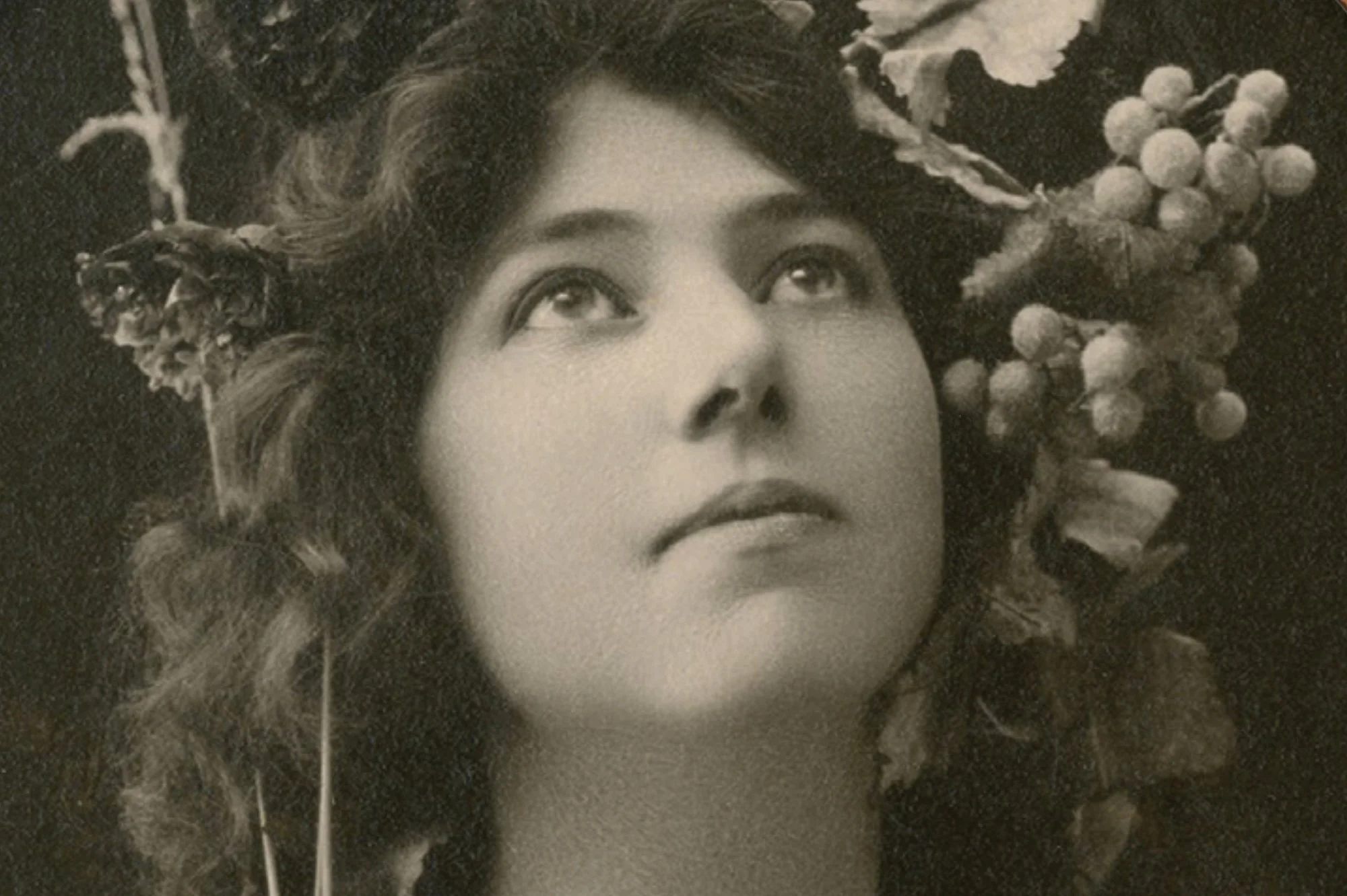 A woman with curly hair looking upward, surrounded by floral arrangements with berries and flowers.
