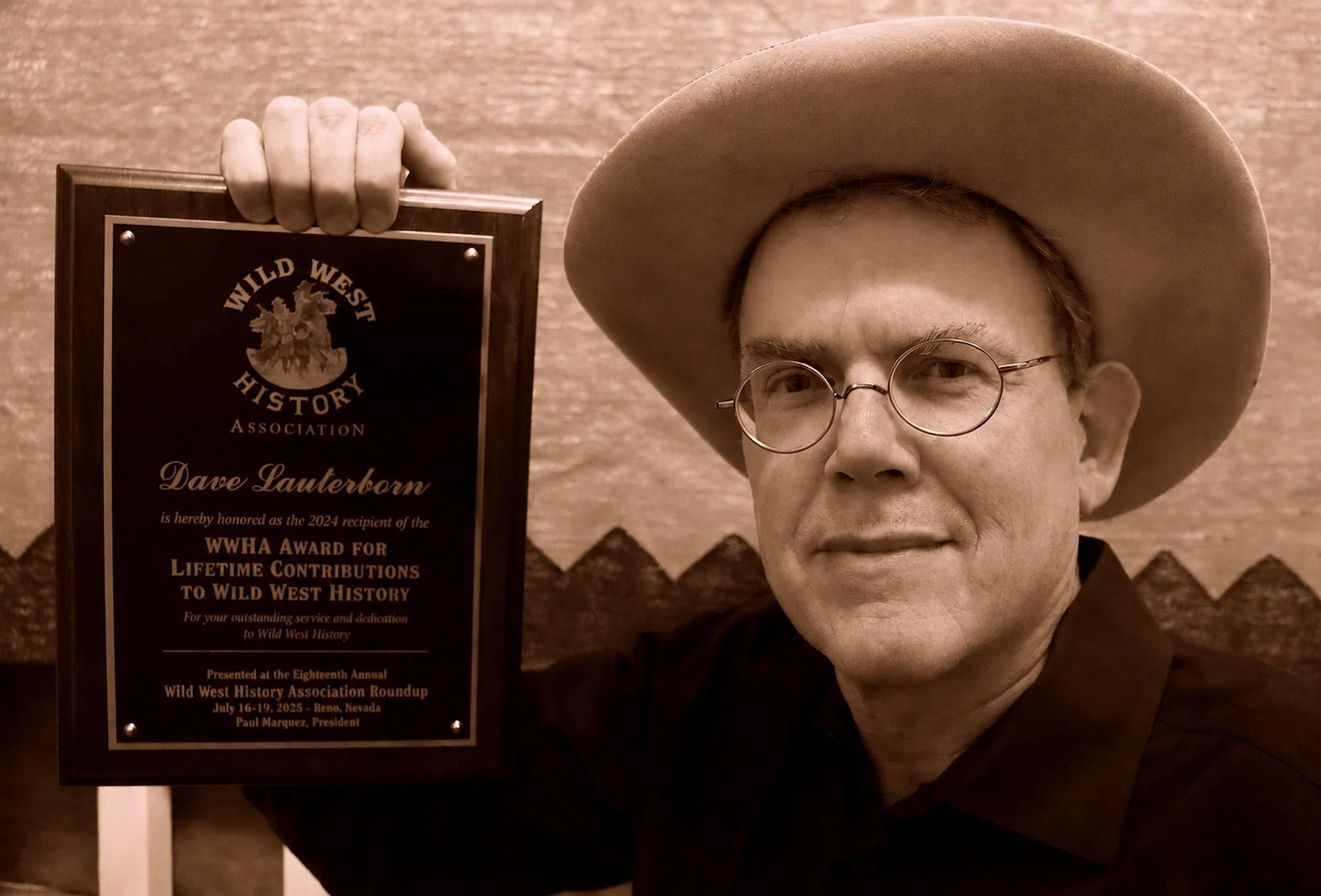 David Lauterborn holds up his 2025 Six Shooter Award for Lifetime Achievements in Western Literature from the Wild West History Association.