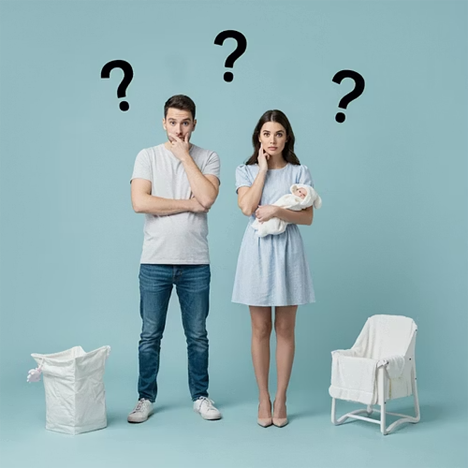 A man and woman standing next to each other, each with a question mark above their heads. The woman is holding a newborn baby. There are baby items, including a crib and a changing table, in the scene.